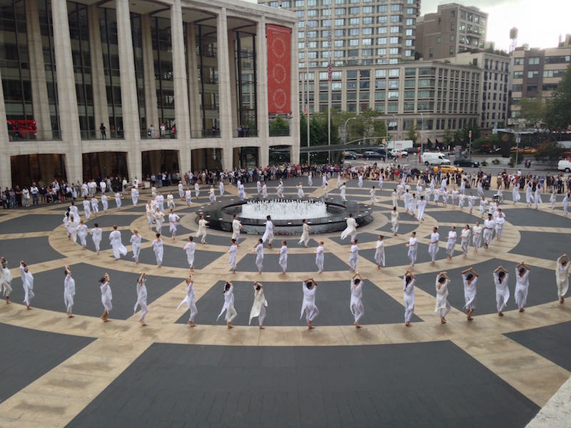 Some dancers sit crosslegged while other lean against the plaza's center fountain